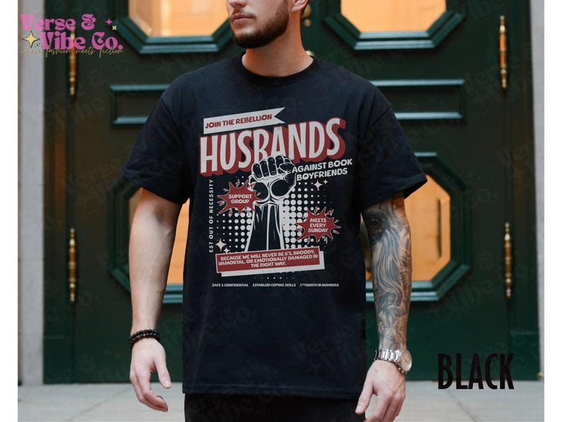 以下が含まれることがあります： 「Join the Rebellion: Husbands Against Book Boyfriends」というテキストと、拳を突き上げたグラフィックがプリントされた黒いTシャツ。グラフィックには、「Support Group」、「Meets Every Sunday」、「Est Out of Necessity」というテキストも含まれています。
