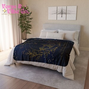 K&ouml;nnte beinhalten: Eine marineblaue Tagesdecke mit einem goldenen Sternbild-Design und dem Text "Glaube an die Magie, die in dir steckt". Die Decke liegt auf einem Bett mit wei&szlig;en Bettw&auml;sche und einem wei&szlig;en Kissen.
