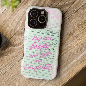 May include: A phone case with a light green and white design featuring a library card theme. The case has the text "buy me books and tell me I'm pretty" in pink script. The case has a camera cutout.