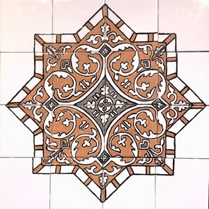 May include: A brown and white ceramic tile with a geometric pattern of stylized leaves and flowers. The tile has a white background with brown and black outlines.