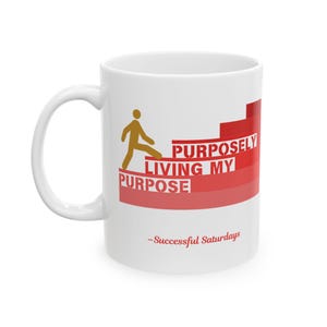 May include: White ceramic mug with a curved handle. The mug features a gold-colored stick figure climbing red steps, with the words "PURPOSELY LIVING MY PURPOSE" in red. Below, the text "-Successful Saturdays" is printed in red.