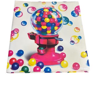 Puede incluir: Una tela blanca doblada con una ilustraci&oacute;n de una m&aacute;quina de chicles. La m&aacute;quina rosa tiene un globo transparente lleno de chicles de colores. Chicles de varios tama&ntilde;os en tonos azules, amarillos y rosas est&aacute;n dispersos.