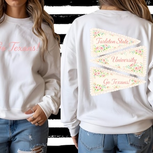 May include: White sweatshirt with the text "Go Texans!" in pink on the front. The back features three pennant-shaped designs with floral patterns and the words "Tarleton State University" and "Go Texans!"