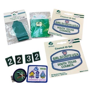 May include: A collection of Girl Scout patches and insignia tabs. Includes a green insignia tab, Council ID sets with blue and white patches, number patches, and a Community Service patch with birdhouses.