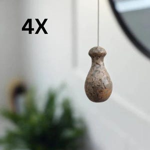 May include: A set of 4X light brown, pear-shaped light pull handles with a mottled, dark brown speckled pattern. Each handle features a smooth, rounded top and a wider, bulbous base, suspended by a thin white cord for ceiling light operation.