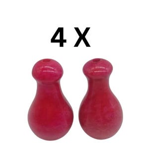 May include: Four pink, pearlescent, wooden bottle stoppers. The stoppers are shaped like a teardrop with a small hole at the top.