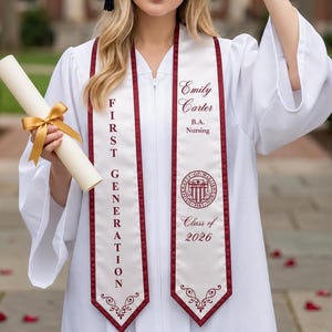 May include: A woman in a white graduation gown and black mortarboard cap holds a diploma tied with a gold ribbon. The sash reads "First Generation" and "Emily Carter B.A. Nursing Class of 2026".
