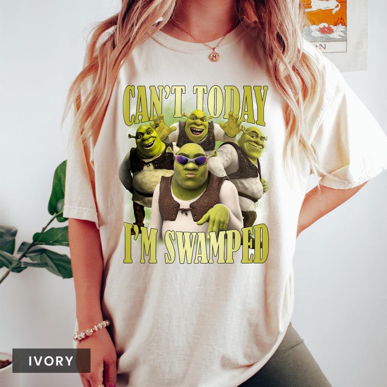 May include: A white t-shirt with a green Shrek character graphic. The text "Can't Today I'm Swamped" is printed on the shirt.
