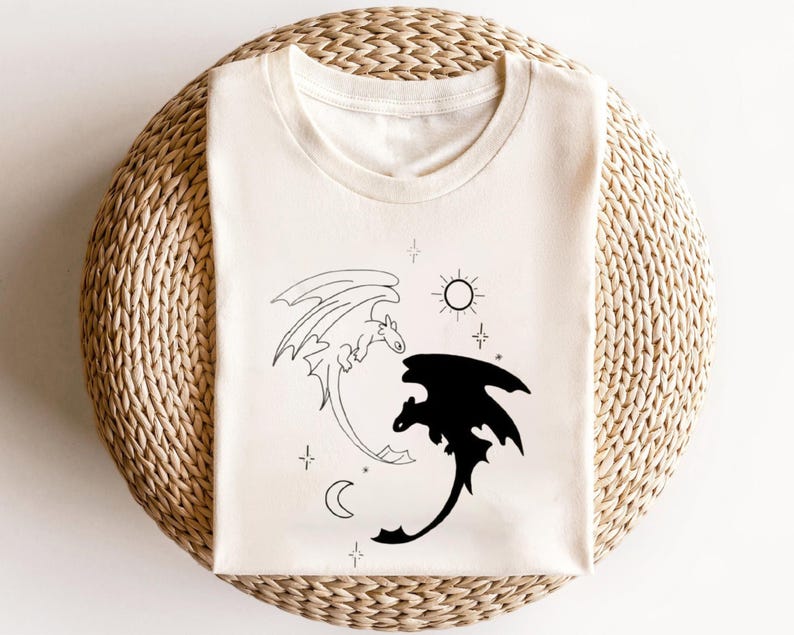 May include: White t-shirt with a black and white illustration of two dragons, one white and one black, with stars, a sun, and a moon in the background.