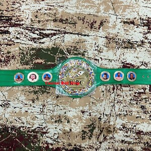 May include: A green leather boxing championship belt with gold accents and a large gold plate in the centre. The plate features the text "World Boxing Council" and the WBC logo. There are three smaller plates with photos of boxers on the belt.