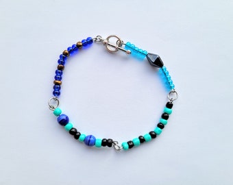 May include: A blue, turquoise, and black beaded bracelet with a silver clasp.