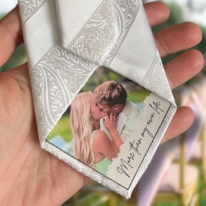 foto van een prachtige witte stropdas met bloemen patroon (tevens wit). Aan de achterzijde is een gepersonaliseerde foto op canvas bevestigd.