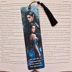 Può includere: Segnalibro con illustrazione fantasy di un uomo e una donna dai capelli scuri. Il segnalibro ha un nappa nera e il testo: "FOR THOSE WHO LIVE THEIR NIGHTMARES, SO THAT OTHERS MAY HAVE THEIR DREAMS."