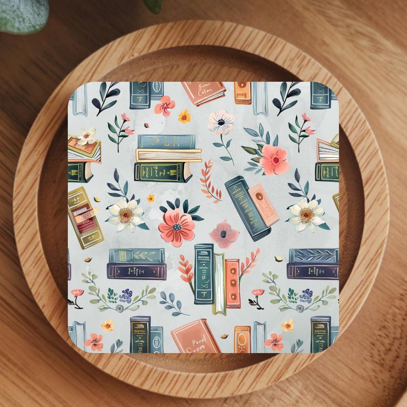 May include: Square coaster with a pale blue background featuring a pattern of books and flowers in shades of pink, orange, and green. The books are in various sizes and colours.