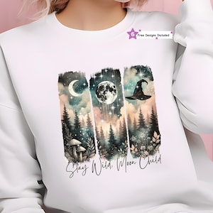 May include: White sweatshirt featuring a watercolor design with a crescent moon, full moon, and witch hat over a forest scene. The text "Stay Wild, Moon Child" is printed below the design. Includes "6 Free Designs Included" text.