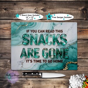 May include: A rectangular cutting board with a teal marble design and gold accents. The text "IF YOU CAN READ THIS SNACKS ARE GONE IT'S TIME TO GO HOME" is displayed. A knife and chopped vegetables are in the foreground.