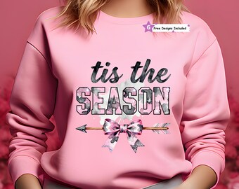 Puede incluir: Sudadera rosa con el texto "tis the SEASON" en letras de camuflaje negras y grises. Un gráfico de arco y flecha con un lazo de camuflaje rosa está debajo del texto. También es visible una estrella con "6 Free Designs Included".