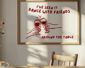 May include: A framed print with the text "I'VE SEEN IT DANCE WITH FRIENDS AROUND THE TABLE" in red. The image features two wine glasses clinking, with hands holding them. The frame is a light brown color, and the background is white.