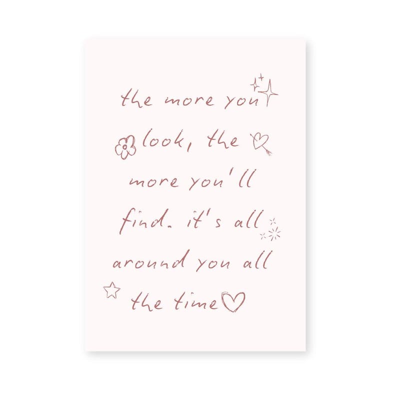 May include: A rectangular, off-white card with handwritten text in a soft, reddish-brown color. The text reads: "the more you look, the more you'll find. it's all around you all the time."