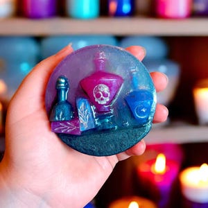 May include: A round, purple and blue soap bar with a skull and crossbones design. The soap features a variety of bottles and other decorative elements.