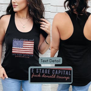 May include: Black tank top featuring an American flag graphic with the text "stars stripes and LATE STAGE CAPITALISM fuck donald trump." The top has a racerback design and is worn by a person.