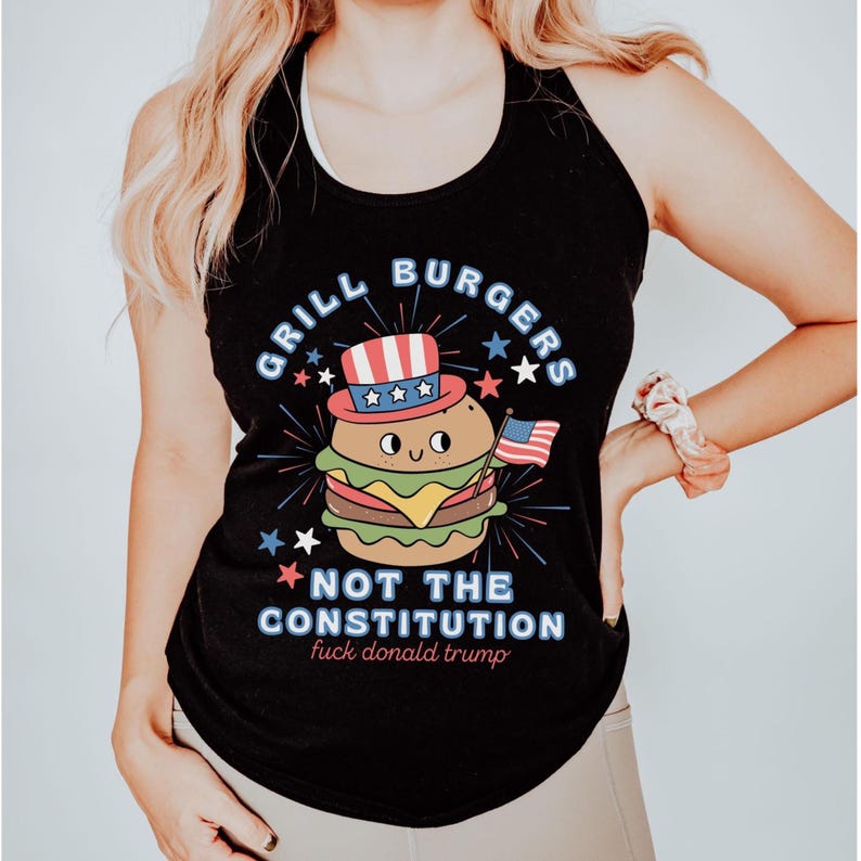 May include: Black tank top featuring a burger character in a patriotic hat and holding a small American flag. Text reads "Grill Burgers Not The Constitution" with additional text below.