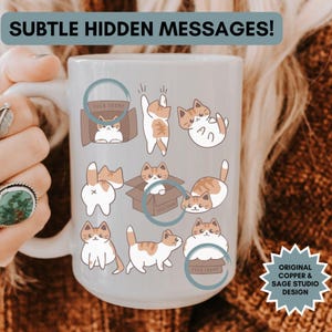 Peut inclure: Mug en céramique blanche avec une anse, orné d'illustrations de chats roux et blancs dans diverses poses. Le mug porte les inscriptions "SUBTLE HIDDEN MESSAGES!" et "ORIGINAL COPPER & SAGE STUDIO DESIGN".