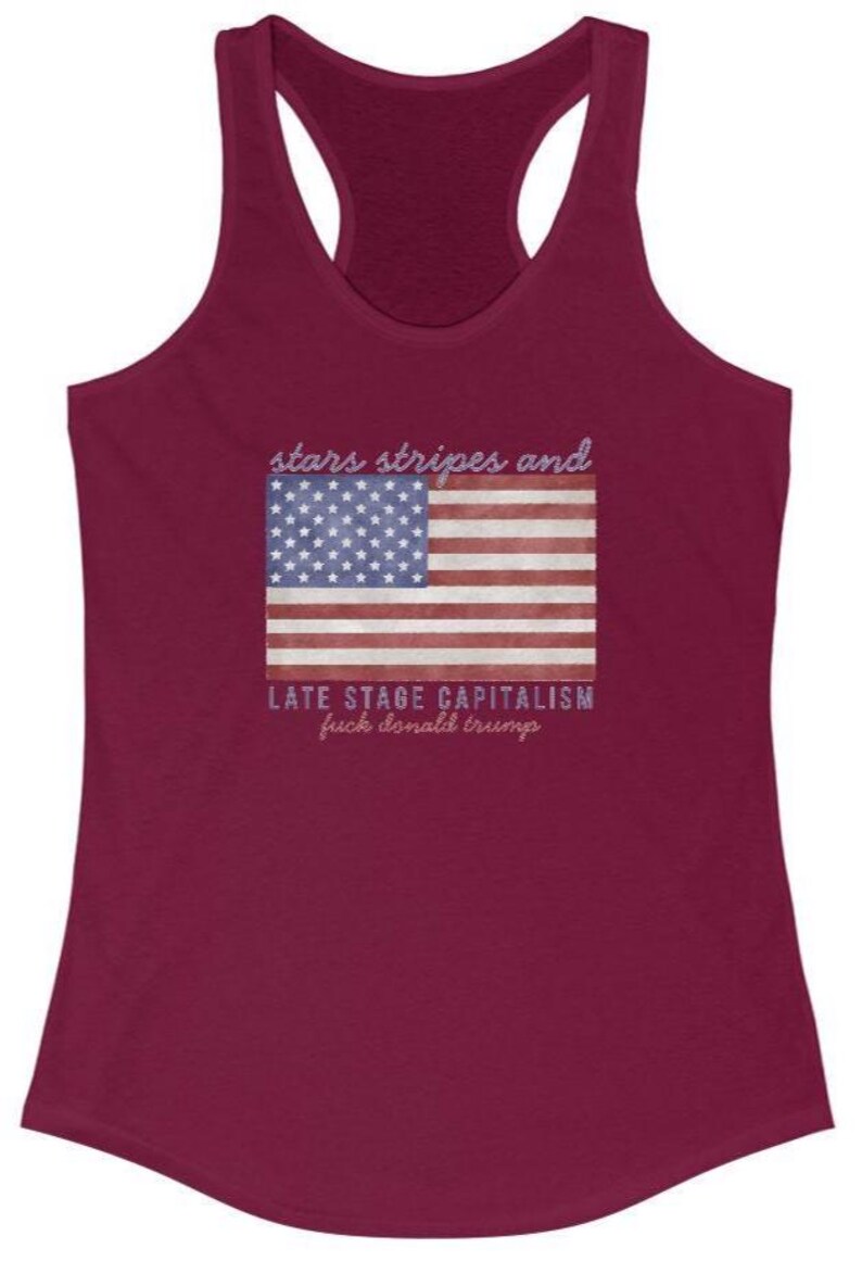 May include: Burgundy racerback tank top with a graphic of the American flag and the text "stars stripes and LATE STAGE CAPITALISM fuck donald trump" in a distressed font. The top has a scoop neck and a racerback design.