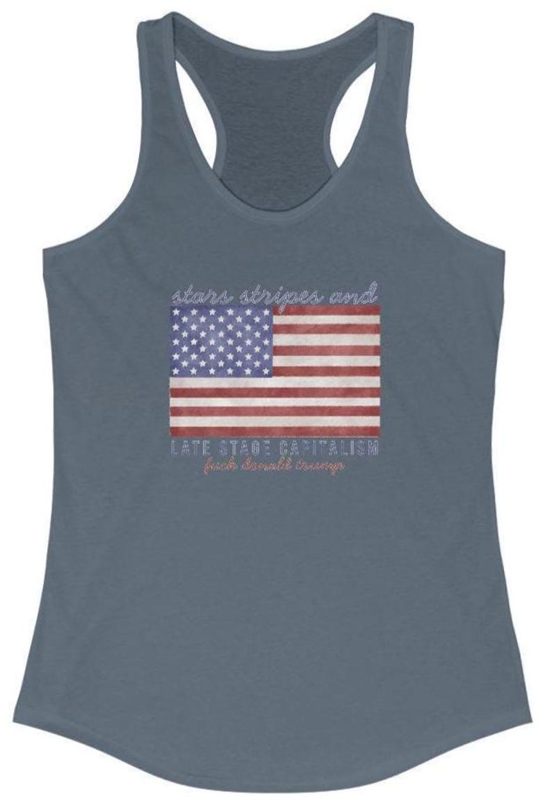 May include: A blue racerback tank top featuring an American flag design. The flag graphic includes the text "stars stripes and" above the flag and "LATE STAGE CAPITALISM from donald trump" below the flag.