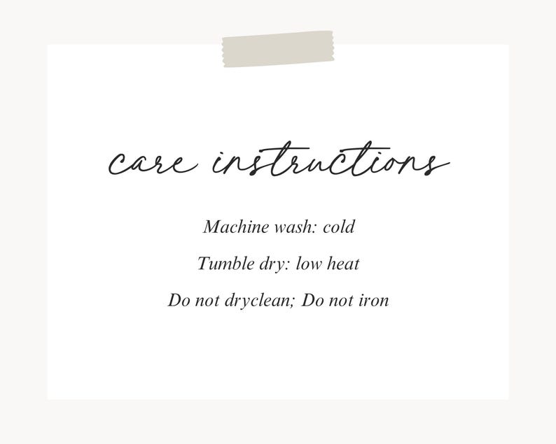 Pu&ograve; includere: Una scheda bianca con le parole "care instructions" in elegante scrittura. Sotto, elenca i dettagli di cura: lavare in lavatrice a freddo, asciugare in asciugatrice a bassa temperatura, non lavare a secco e non stirare. Un pezzo di nastro adesivo &egrave; in alto.
