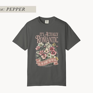 Pu&ograve; includere: T-shirt color pepe con grafica floreale e la scritta "IT'S ACTUALLY ROMANTIC ALL THE EFFORT YOU PUT IN". La grafica presenta fiori rosa, bianchi e gialli disposti a cerchio.