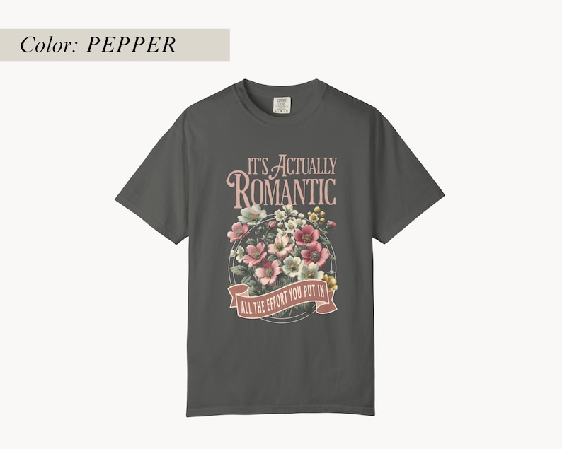 Pu&ograve; includere: T-shirt color pepe con grafica floreale e la scritta "IT'S ACTUALLY ROMANTIC ALL THE EFFORT YOU PUT IN". La grafica presenta fiori rosa, bianchi e gialli disposti a cerchio.