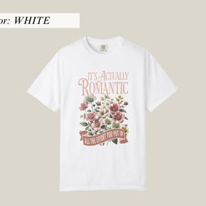 Pu&ograve; includere: T-shirt bianca con design floreale e la scritta "IT'S ACTUALLY ROMANTIC / ALL THE EFFORT YOU PUT IN" in stile vintage. I fiori sono nelle tonalit&agrave; del rosa, bianco e verde.