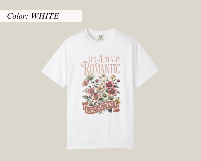 Pu&ograve; includere: T-shirt bianca con design floreale e la scritta "IT'S ACTUALLY ROMANTIC / ALL THE EFFORT YOU PUT IN" in stile vintage. I fiori sono nelle tonalit&agrave; del rosa, bianco e verde.