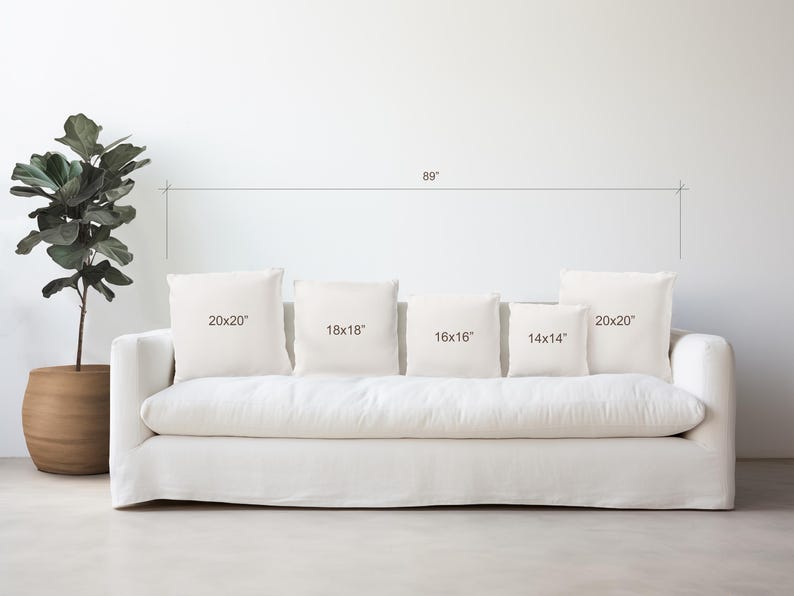 May include: A white sofa with five white throw pillows of different sizes. The pillows are labeled with their dimensions: 20x20 inches, 18x18 inches, 16x16 inches, 14x14 inches, and 20x20 inches.