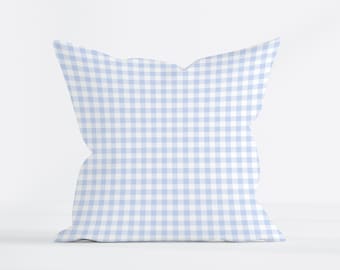Può includere: Un cuscino decorativo blu chiaro con un motivo a quadri bianchi.