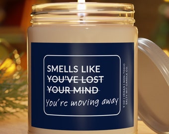 May include: A white candle in a glass jar with a blue label that reads "Smells like you've lost your mind You're moving away".