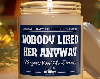 Könnte beinhalten: Eine weiße Kerze in einem Glasgefäß mit einem blauen Etikett, auf dem "Nobody Liked Her Anyway (Congrats On The Divorce)" und "Salty Wit Candle Co." steht.