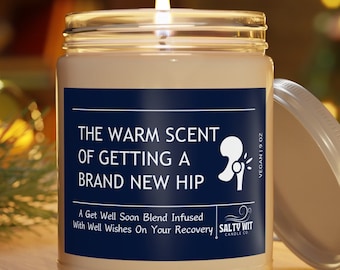 May include: A white candle with a blue label that reads "The Warm Scent of Getting a Brand New Hip. A Get Well Soon Blend Infused With Well Wishes On Your Recovery." The candle is in a glass jar with a silver lid. The candle is lit and the flame is visible.