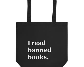 Puede incluir: Bolsa de tela negra con texto blanco que dice "Leo libros prohibidos."