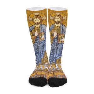 Puede incluir: Calcetines hasta la rodilla con un diseño de icono religioso. Los calcetines muestran dos figuras con túnicas azules, sosteniendo libros, sobre un fondo dorado. Los calcetines tienen puntera negra y fondo blanco. El diseño es similar a un mosaico.