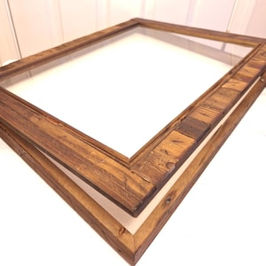 May include: A rectangular wooden picture frame with a glass pane. The frame is made of reclaimed wood with a natural, rustic finish. The frame is open, with the glass and back separated.