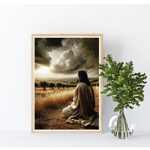 May include: A framed print of a man in a white robe kneeling in a field with a cloudy sky and a sunset in the background.