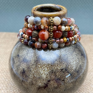 Rust and creams multi colors glass and gemstone beads five strand women&#39;s seven inch bracelet. Antique gold bead accents and magnetic clasp.