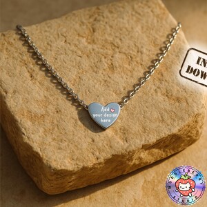 May include: A silver-colored necklace with a heart-shaped pendant. The pendant is light blue and has the text "Add your design here". The image also includes a "Instant Download" stamp.