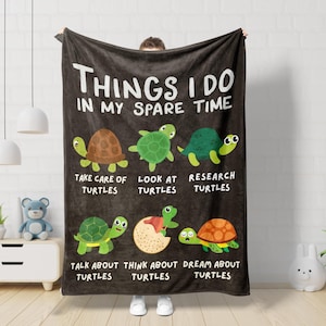 May include: A black fleece blanket with the text "Things I do in my spare time" and illustrations of turtles. The text below the turtles reads "Take care of turtles", "Look at turtles", "Research turtles", "Talk about turtles", "Think about turtles", and "Dream about turtles".