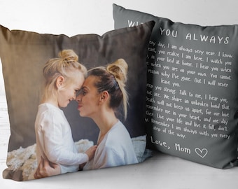 Op de afbeelding: Twee vierkante sierkussens met een aangepast ontwerp. Eén kussen toont een fotoprint van een kind en een volwassene die elkaar aankijken. Het tweede kussen is donkergrijs met witte tekst "WITH YOU ALWAYS" en "Love, Mom" met een hartje.
