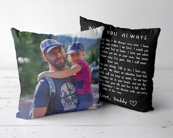 Op de afbeelding: Twee vierkante kussens. Eén kussen toont een kleurenfoto van een man met een baseballpet en een t-shirt die een jong kind met een baseballpet en een roze shirt vasthoudt. Het andere kussen is zwart met witte tekst en een hartje.