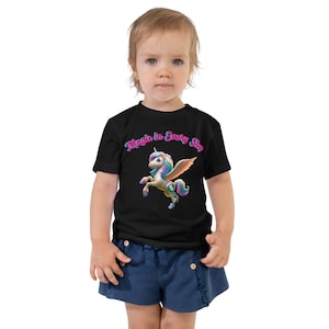 May include: A black t-shirt with a colorful unicorn graphic and the text "Magic in Every Step".