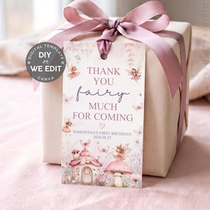 May include: A rectangular gift tag with a fairy theme, featuring illustrations of fairies, a mushroom house, and butterflies. The text reads: THANK YOU fairy MUCH FOR COMING, SAMANTHA'S FIRST BIRTHDAY, 2028.08.25. The tag is tied to a gift box with a pink ribbon.